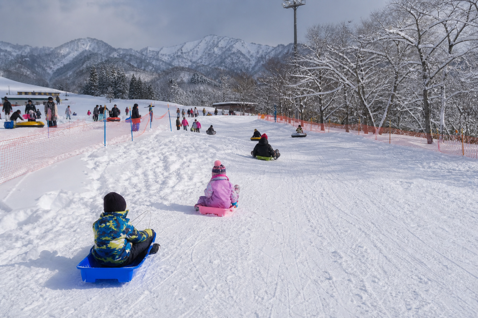 雪の滑り台で遊ぶ家族——緩やかな初級斜面